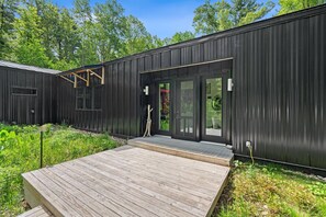 Ein modernes, schwarzes Gebäude aus Metall mit einer Holzdielen-Terrasse und Glasüren.
