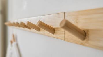 A wooden coat rack with multiple hooks against a white wall.