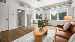 Una sala de estar moderna con un sofá de cuero marrón, una mesa de centro de madera y un comedor con mesa y sillas.