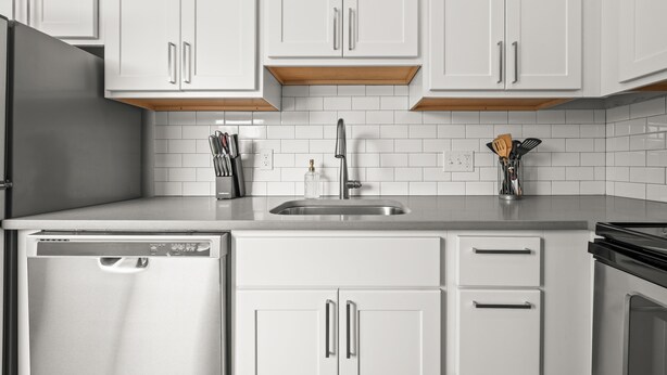 Una cocina moderna con armarios blancos, lavavajillas de acero inoxidable y estufa negra.