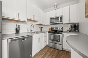 Una cocina moderna con armarios blancos, electrodomésticos de acero inoxidable y suelo de madera.