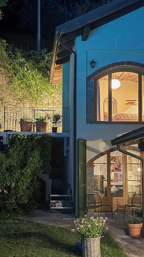 Ein zweistöckiges Haus mit Balkon, Blumentöpfen und einem sichtbaren Innenraum mit Möbeln.