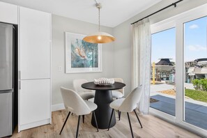 Eine moderne Küche mit Essbereich, einem großen Fenster mit Ausblick und einer Deckenleuchte.