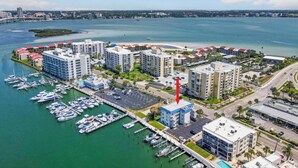 A marina with boats, a coastal cityscape, and high-rise buildings with a red arrow pointing to a specific building. - Bayfront Waterview Newly Upgraded Condo Clearwater Beach (Clearwater)