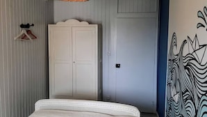 Una camera da letto con un letto, un armadio, una lampada a sospensione e una parete con un disegno grafico.