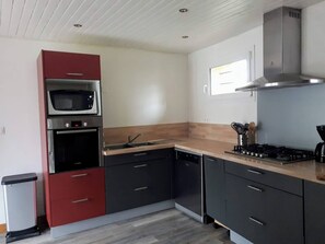 A modern kitchen with a microwave, oven, dishwasher, and gas stove. - Cosy house & private garden - Beaches 5 min away (Tourville-sur-Sienne)