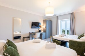 Habitación de hotel con dos camas, un escritorio, un televisor y un ventanal grande.