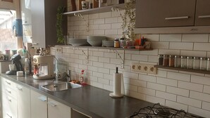 Een moderne keuken met witte metrotegels, roestvrijstalen apparatuur en een ingebouwde gasfornuis.