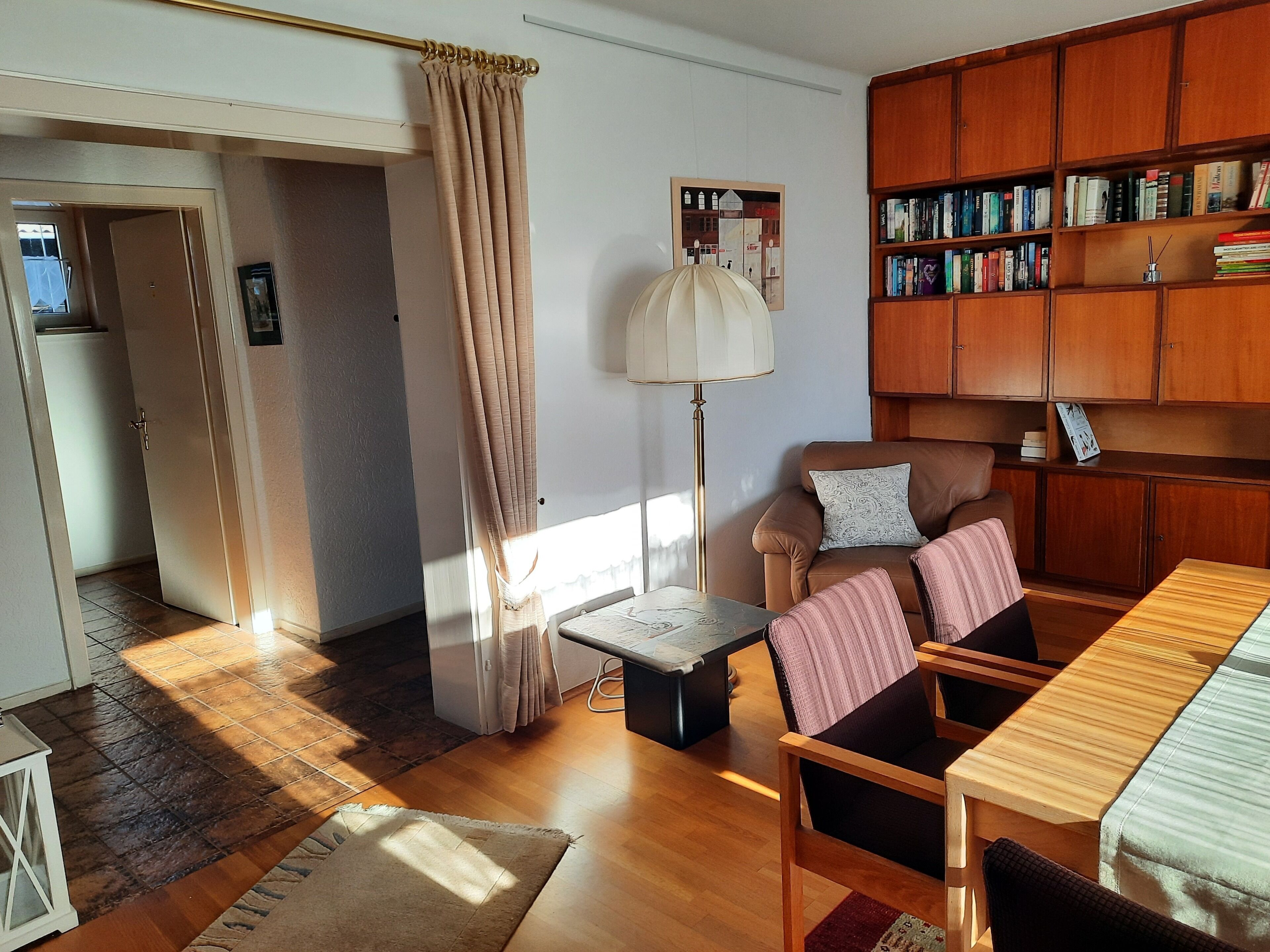 En hyggelig stue med sofa, sofabord, bogreol og lampe.