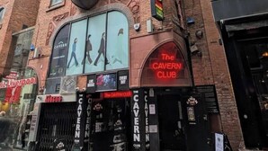 Um edifício de tijolos com um grande letreiro do 'The Cavern Club' e um cartaz dos Beatles.