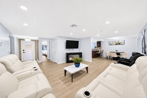 Ein modernes Wohnzimmer mit Kamin, Flachbildfernseher und Essbereich.
