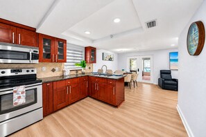 A modern kitchen with wooden cabinets, stainless steel appliances, and a dining area with a view. - Private Pool Retreat in Tampa | 5BR/5BA Vacation Home (Tampa)