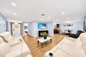 A modern living room with a fireplace, a dining area, and a kitchen in the background. - Private Pool Retreat in Tampa | 5BR/5BA Vacation Home (Tampa)
