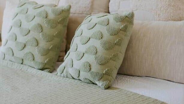 A bed with two pillows, a wall with a painting, and a sofa with cushions. - Villa Oleander: Pool & Rooftop Cinema (Splitska)