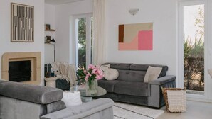 A modern living room with a fireplace, grey sofas, a glass coffee table, and a large window with a view. - Villa Oleander: Pool & Rooftop Cinema (Splitska)