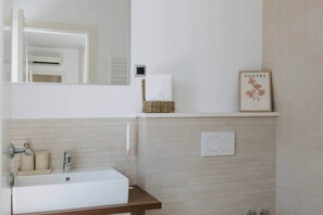 A bathroom with a white sink, a mirror, a towel rack, a framed picture, and a thermostat. - Villa Melograno: Pool & Rooftop Cinema (Splitska)