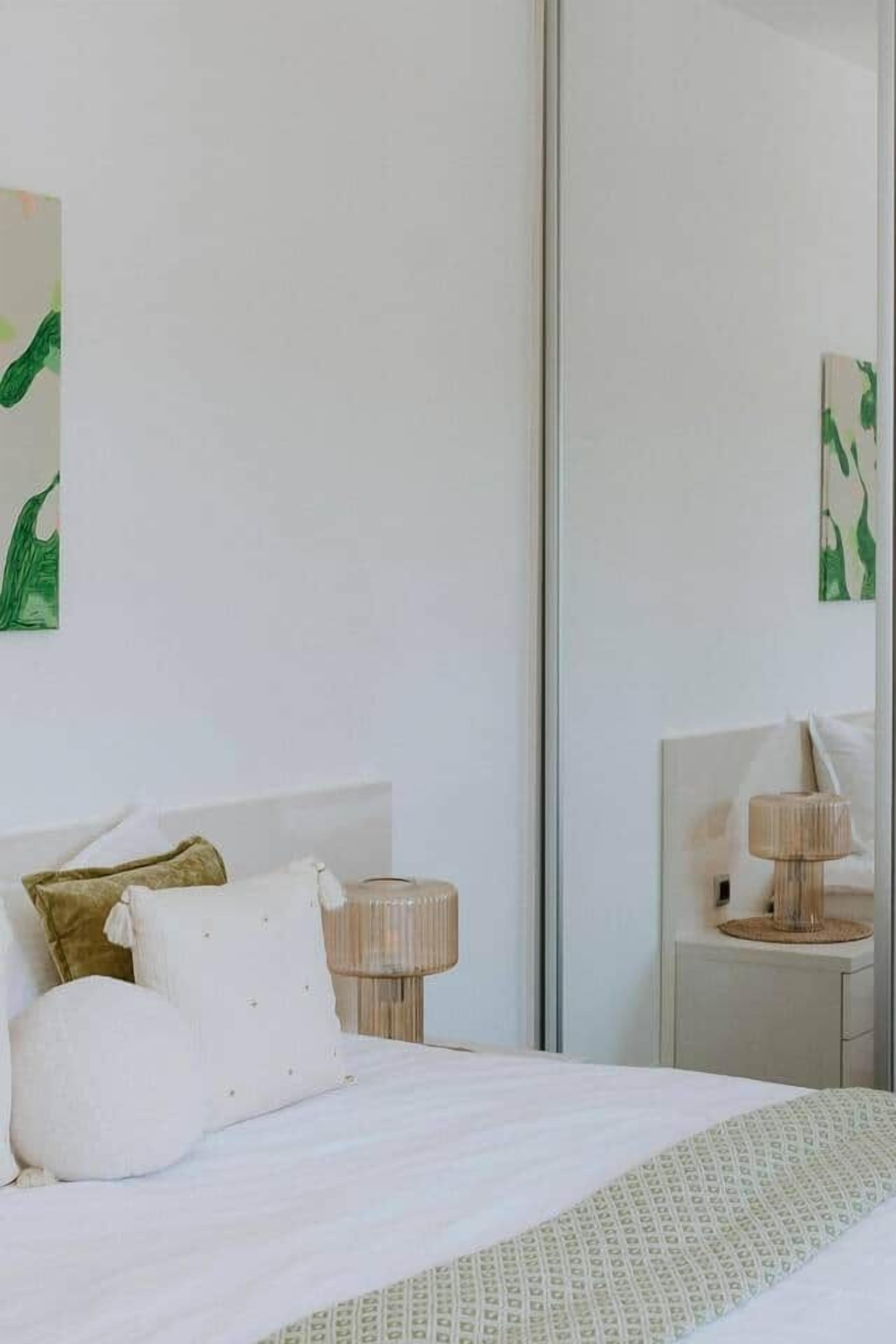 Een hotelkamer met een bed, nachtkastjes, een lamp en kunst aan de muur.
