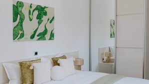 A bedroom with a bed, pillows, a bedside lamp, and a green abstract painting on the wall. - Villa Melograno: Pool & Rooftop Cinema (Splitska)