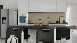 A modern kitchen with white cabinets, a stainless steel refrigerator, a built-in oven, and a large island with a sink. - Villa Melograno: Pool & Rooftop Cinema (Splitska)