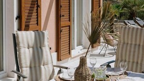 An outdoor dining area with a table set for two, surrounded by wicker chairs and a wicker vase. - Villa Melograno: Pool & Rooftop Cinema (Splitska)