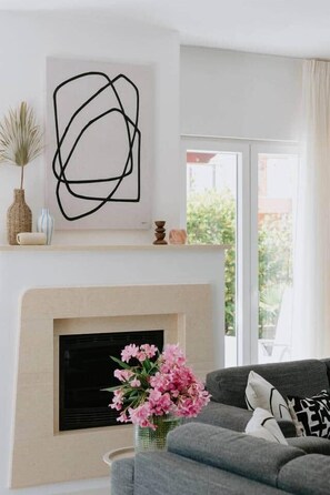 Ein Wohnzimmer mit Kamin, einer Couch und einem an der Wand hängenden abstrakten Kunstwerk.