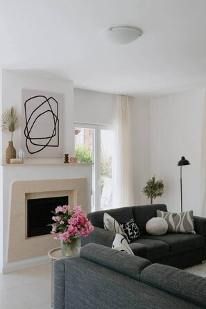 Un salon moderne avec une cheminée, un canapé et un lampadaire.