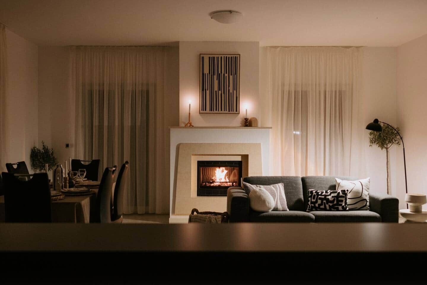 A living room with a fireplace, a sofa, a dining table, and curtains.