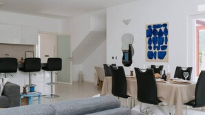 Een moderne eetruimte met een tafel voor vier personen, omringd door zwarte stoelen, en een grijze bank op de voorgrond.