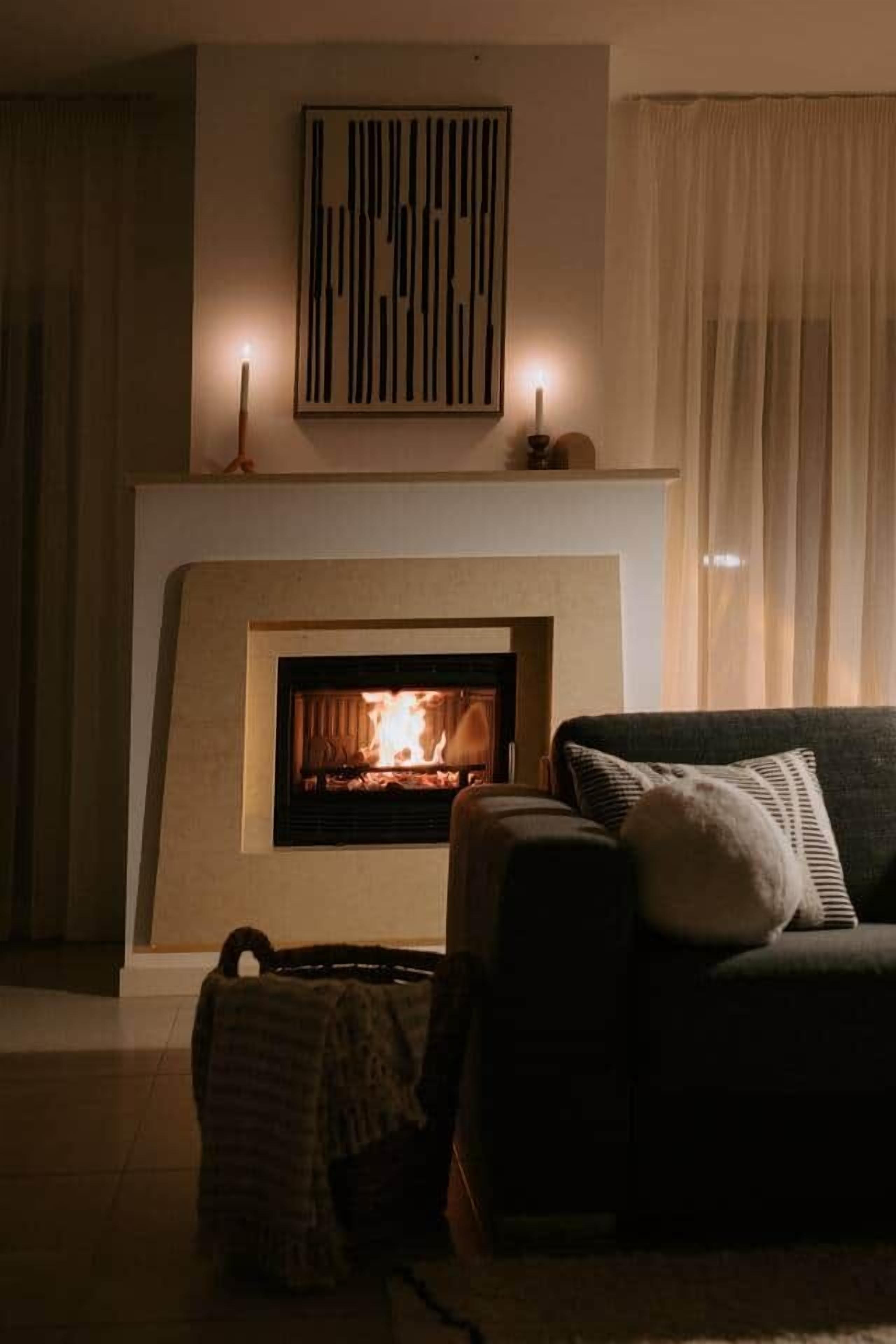 A living room with a fireplace, a sofa, and a wall-mounted artwork.