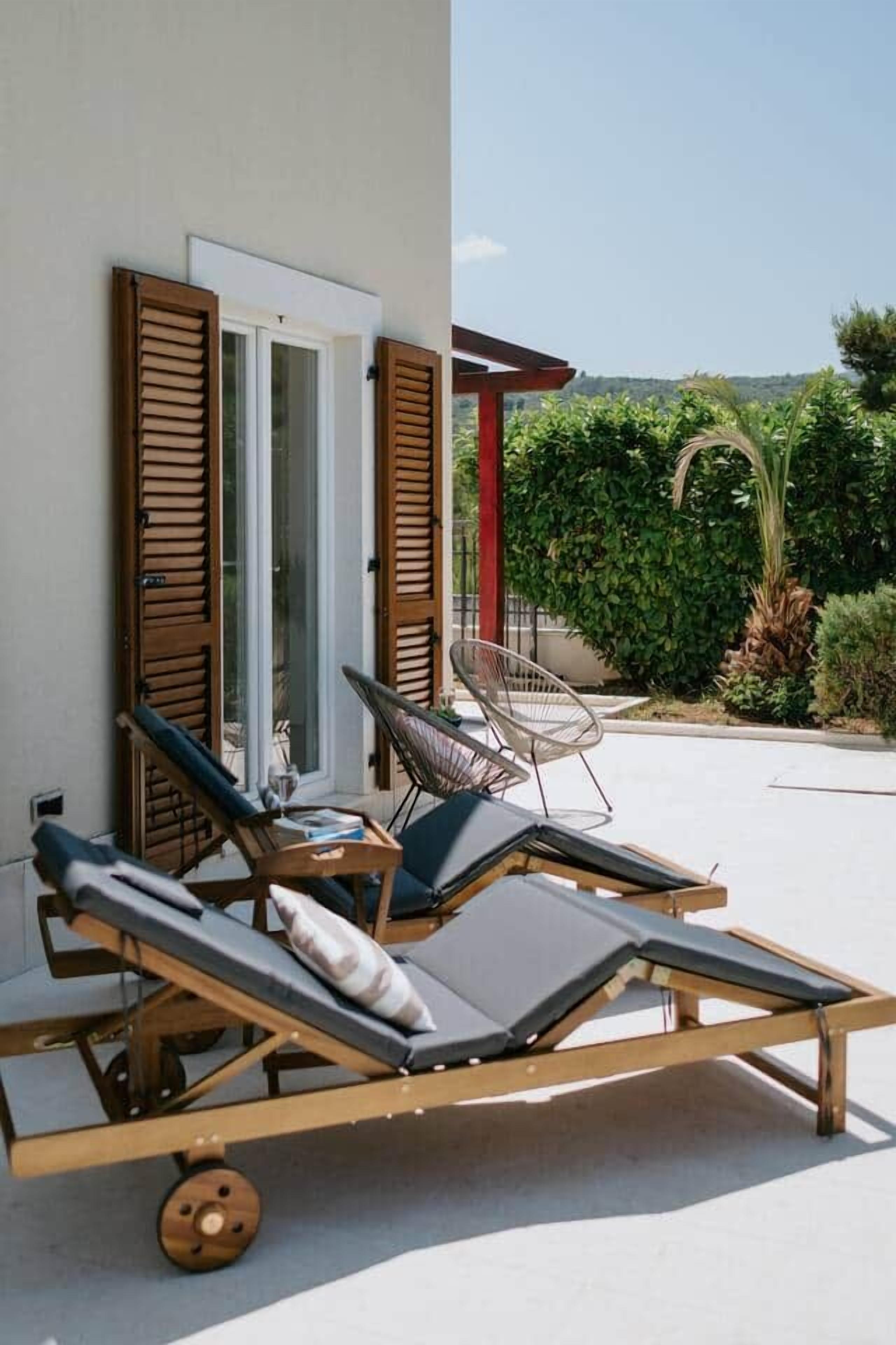 A sun lounger with wheels, a chair, and a table with a glass.