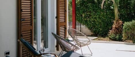 A sun lounger with wheels, a chair, and a table with a glass.