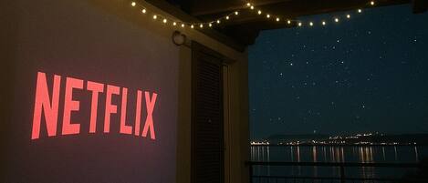 Katettu ulkotila, jossa on valonauhoja, parveke kaiteineen sekä suuri, valaistu kyltti, jossa lukee ”NETFLIX”.