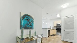 Eine moderne Küche mit Edelstahlgeräten, einem Esstisch mit Glasplatte und einem an der Wand befestigten Kunstwerk.