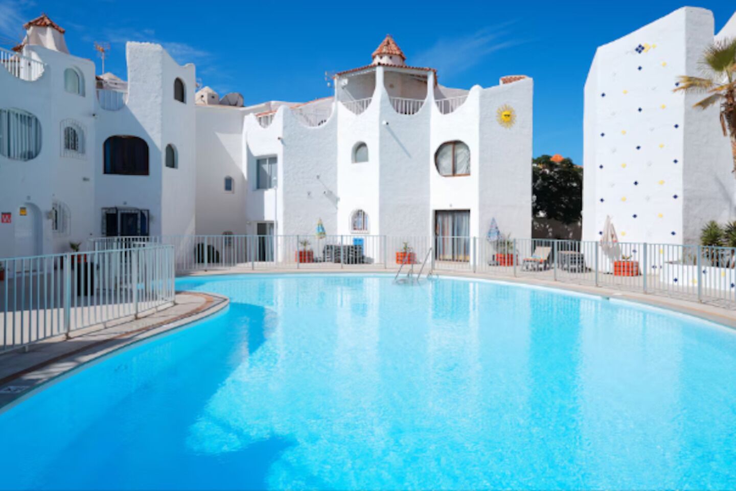 A swimming pool surrounded by white buildings with arched windows and balconies.