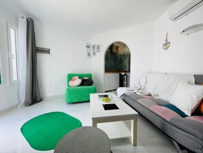 Ein modernes Wohnzimmer mit einem grünen Sofa, einem grauen Sofa, einem weißen Couchtisch und einem kleinen, grünen Ottomanen.