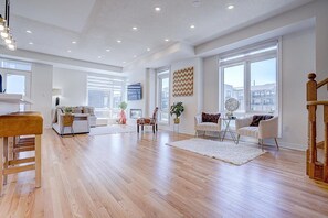A spacious living room with hardwood floors, large windows, and modern furniture.