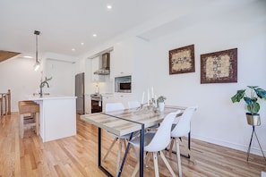 A modern kitchen with white cabinets, a stainless steel refrigerator, and a built-in oven.