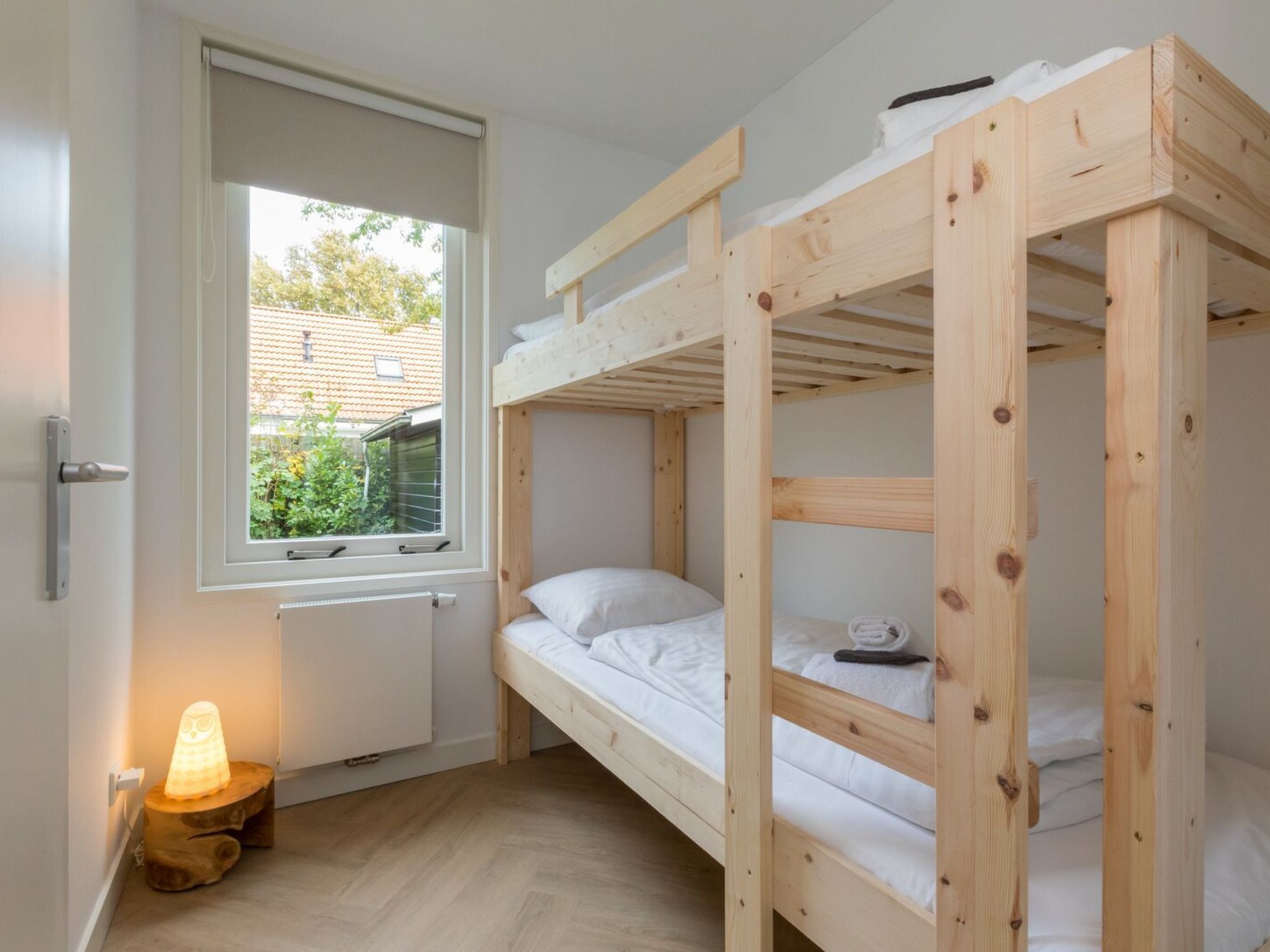Ein Schlafraum mit Etagenbetten, einem Fenster, einer Heizung und einer Nachtlampe.