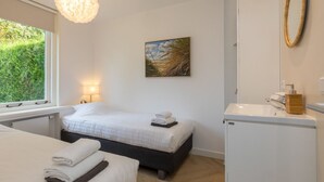 A hotel room with a bed, bedside table, lamp, and a view of greenery outside. - GroenparkHuis by Interhome (Oostkapelle)
