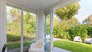 A modern interior with large glass doors leading to a garden. - GroenparkHuis by Interhome (Oostkapelle)