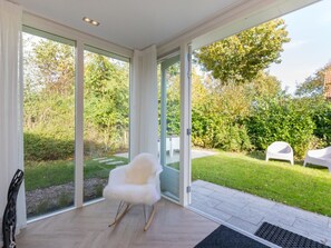 Ein modernes Interieur mit großen Glasüren, die zu einem Garten führen.