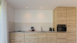 A modern kitchen with wooden cabinets, a built-in oven, and a marble backsplash. - GroenparkHuis by Interhome (Oostkapelle)