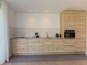 Eine moderne Küche mit Holzschränken, einem eingebauten Ofen und einer Marmor-Spritzschutzwand.
