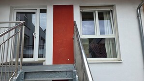A building with a red vertical stripe, a window with curtains, and a metal staircase. - Cozy vacation apartment in HD-Wieblingen (Heidelberg)