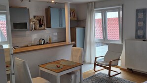 A compact living space with a kitchenette, a dining area, and a seating area with a view. - Cozy vacation apartment in HD-Wieblingen (Heidelberg)