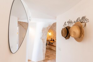 Un bagno con parete in pietra, uno specchio e uno scaffale con cappelli.