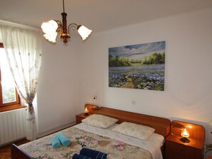 A bedroom with a bed, a painting, a chandelier, and a nightstand. - House Batel by Interhome (Barbariga)