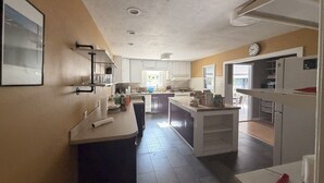Een moderne keuken met witte kasten, een centraal eiland en een eetgedeelte met een tafel en stoelen.