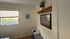 Een kamer met een raam, een lijst met foto, een plant op een plank en een bank met handdoeken.
