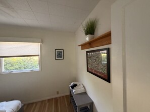 A room with a window, a framed picture, a plant on a shelf, and a bench with towels. - Sleeps 16! - Breaking Away to Bloomington (Bloomington)